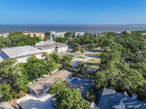 Vista aérea de una zona residencial con casas, una piscina y vista al océano.