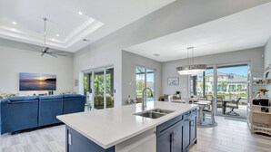 Una cocina moderna con una isla grande, electrodomésticos integrados y vistas al patio exterior.