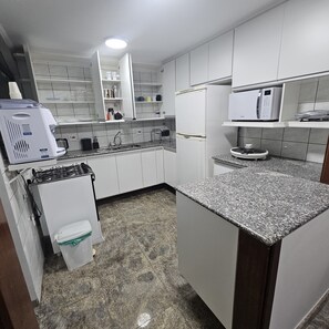 Een koelkast, een magnetron, een kookplaat, kookgerei, borden en bestek