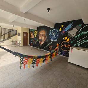 Ein geräumiger Raum mit einer Hängematte, einer Treppe und einer Wand, die mit Wandbildern zum Thema Wissenschaft verziert ist.