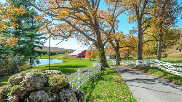 A rural landscape with a paved path, white fence, and autumn-colored trees. - Private Rm 1, Handicap Accessible, 10 quiet acres (Swanton)