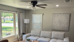 Un soggiorno con ventilatore a soffitto, un divano bianco, un tavolino da caffè e vista sull'esterno.