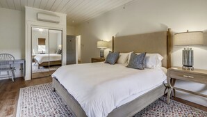 Un dormitorio con una cama grande, mesitas de noche, un espejo y un escritorio.