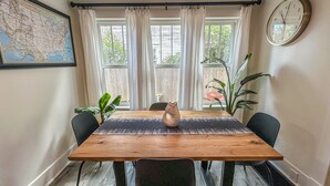 A dining area with a wooden table, black chairs, a map on the wall, and a clock.