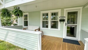 A porch with a wooden deck, white railings, and a mailbox with the number 1110.