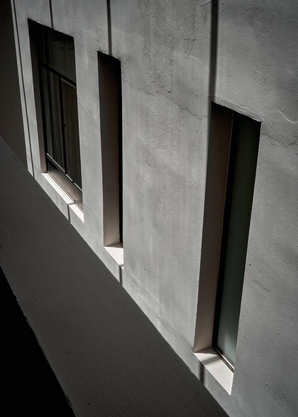 Fachada de edificio con tres ventanas rectangulares alineadas verticalmente.
