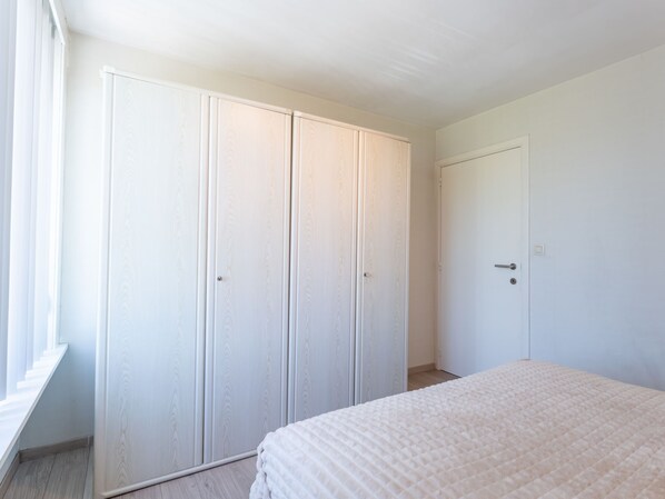 A bedroom with a large wardrobe, a bed, and a window.