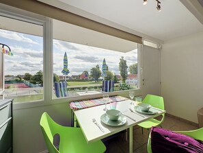 Een eethoek met een tafel voor twee personen, stoelen en uitzicht op buiten.