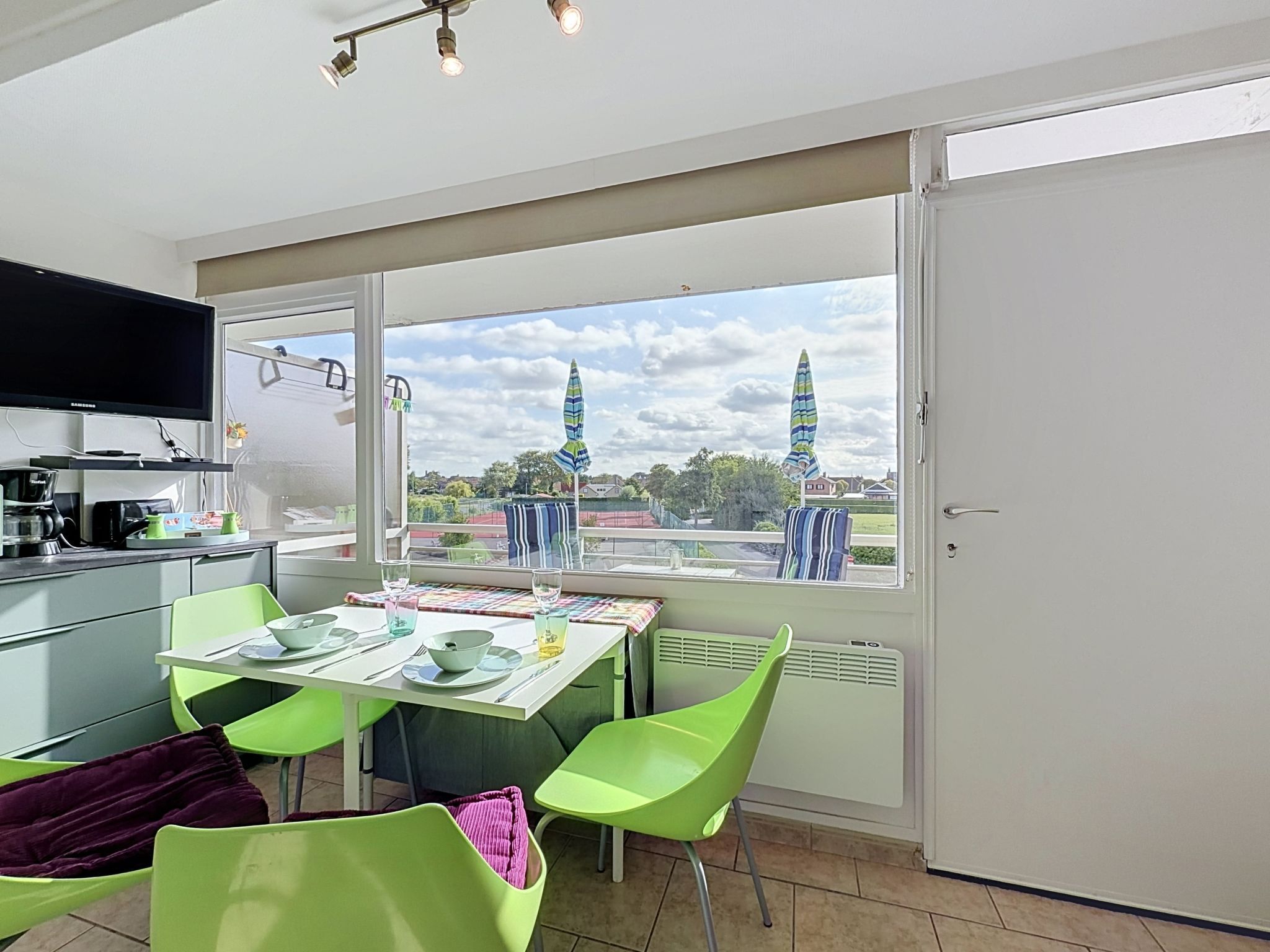 Una cocina moderna con comedor, ventanas amplias y vistas a un pueblo.