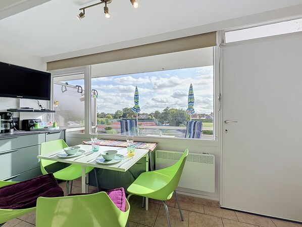 A modern kitchen with a dining area, large windows, and a view of a town.