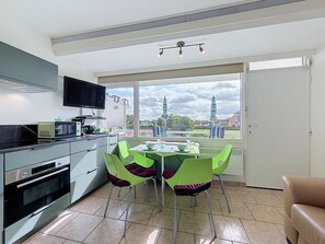 Een moderne keuken met een eethoek, een flatscreen-tv en uitzicht op een stad met een kerktoren.