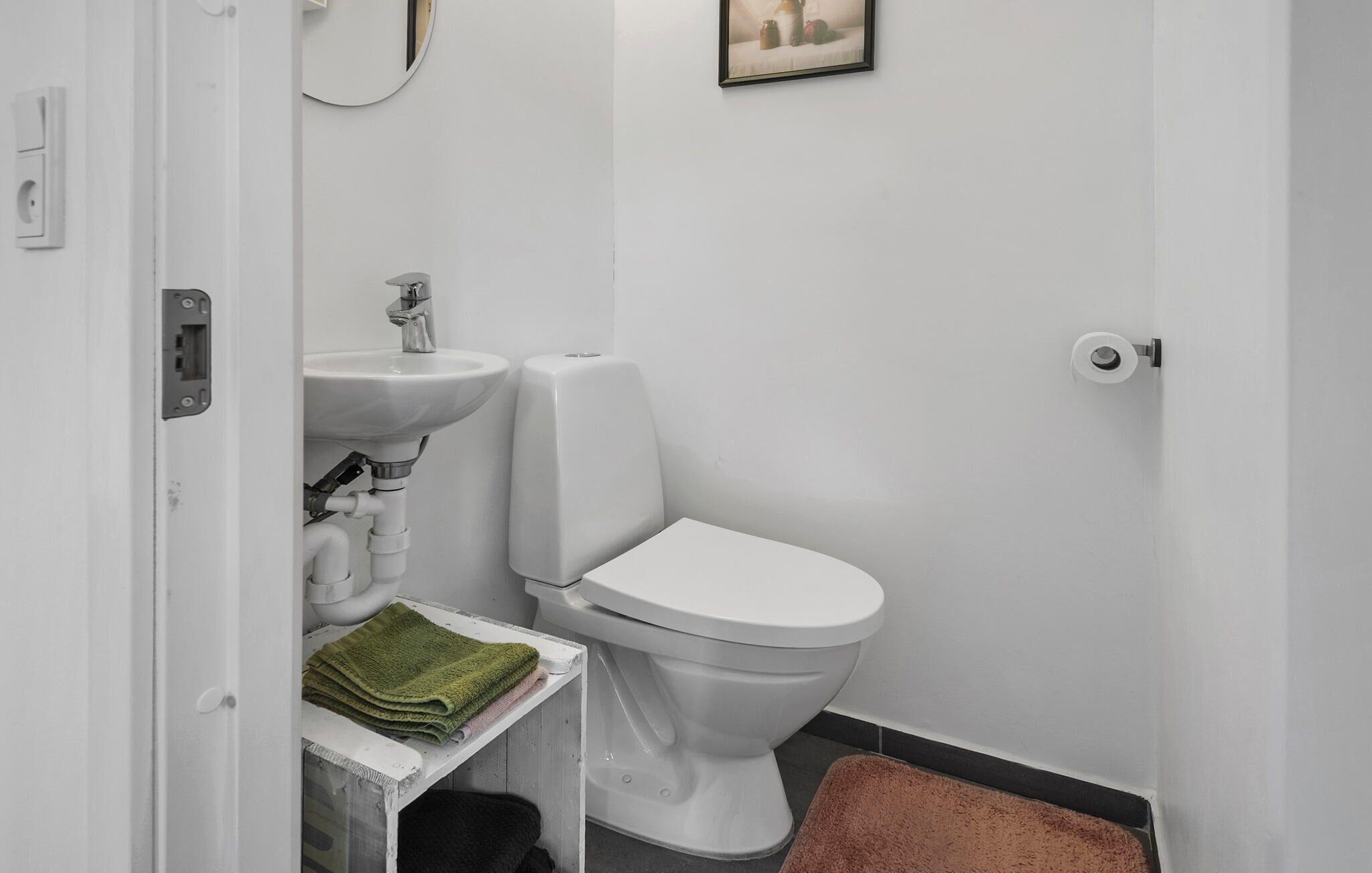 Un bagno piccolo con un lavandino bianco, un water e un portasciugamani con asciugamani piegati.