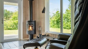 A cozy room with a wood-burning stove, leather seating, and large windows overlooking a garden. - Pet friendly home in Tarm with WiFi (Tarm)