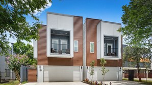 A modern two-story building with a garage, a balcony, and a small garden area. - Elegant and beautiful 3-bedroom townhome near downtown Houston with WiFi, AC (Houston)