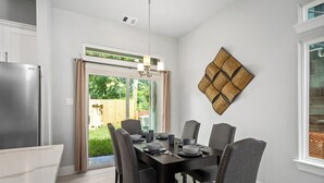 A dining area with a dark wooden table, six grey upholstered chairs, and a modern chandelier. - Elegant and beautiful 3-bedroom townhome near downtown Houston with WiFi, AC (Houston)
