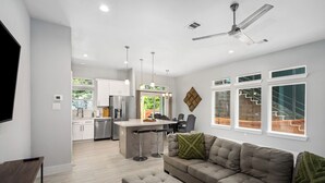 A modern living room with a sofa, ottoman, and a TV stand. - Elegant and beautiful 3-bedroom townhome near downtown Houston with WiFi, AC (Houston)