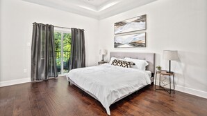 A bedroom with a large bed, a ceiling fan, and a view of greenery through the window. - Elegant and beautiful 3-bedroom townhome near downtown Houston with WiFi, AC (Houston)