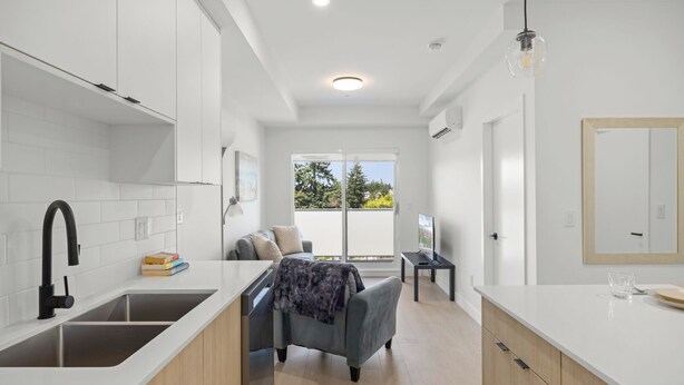 A modern kitchen with white cabinetry, a black faucet, and a dining area with a table and chairs.