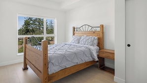 A bedroom with a wooden bed, a window with a view of trees, and a door.