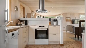 Uma cozinha moderna com forno embutido, máquina de café e chaleira.