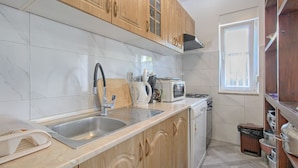 A kitchen with wooden cabinets, a stainless steel sink, a microwave, a stove, and a window.