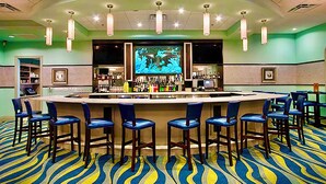 A bar area with a counter, multiple bar stools, and a large screen displaying an image.