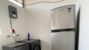 A compact kitchen with a stainless steel refrigerator, a washing machine, and a water dispenser. - Casa Firefly (Puerto Escondido)