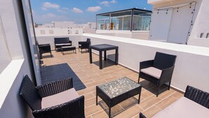 A rooftop terrace with outdoor furniture, including wicker chairs and a table, and a glass enclosure with string lights. - FFamily House & Water Park Tlayecac 3 BR (Ayala)