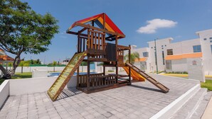 A wooden play structure with a slide and a climbing ladder, set on a paved area with a clear sky. - FFamily House & Water Park Tlayecac 3 BR (Ayala)