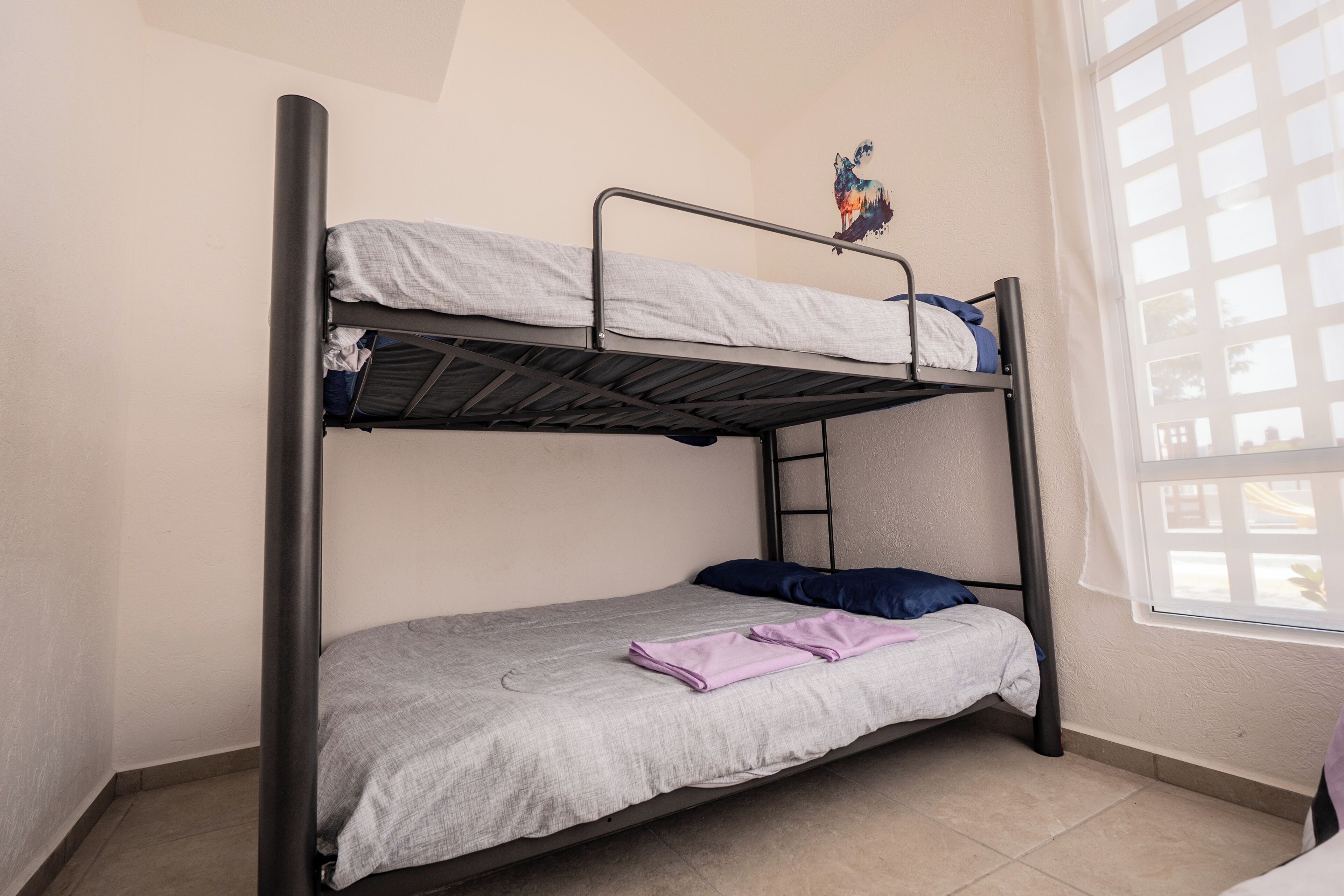 A bunk bed room with a window and a door.