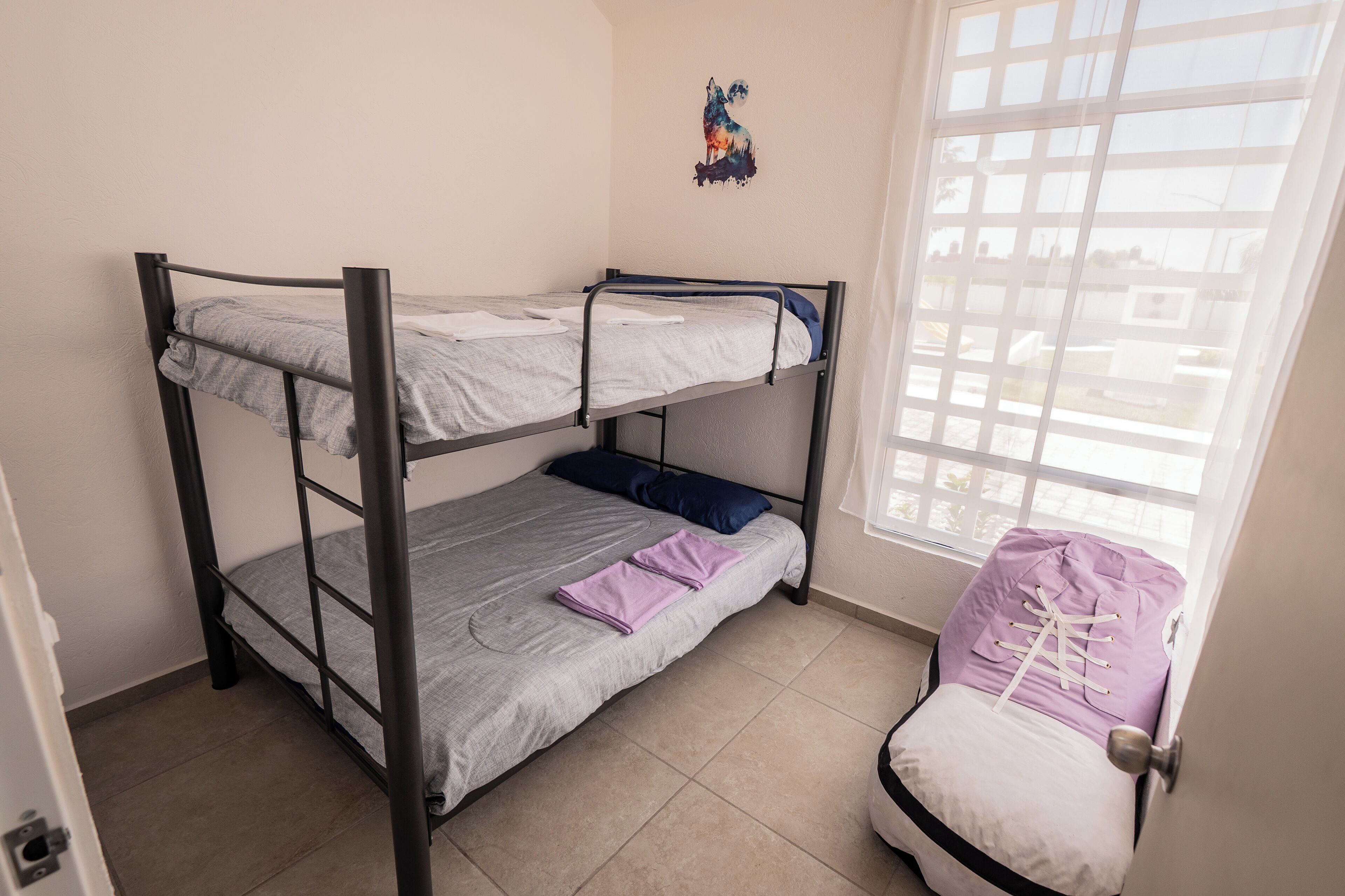 Habitación con literas, ventana y una silla.