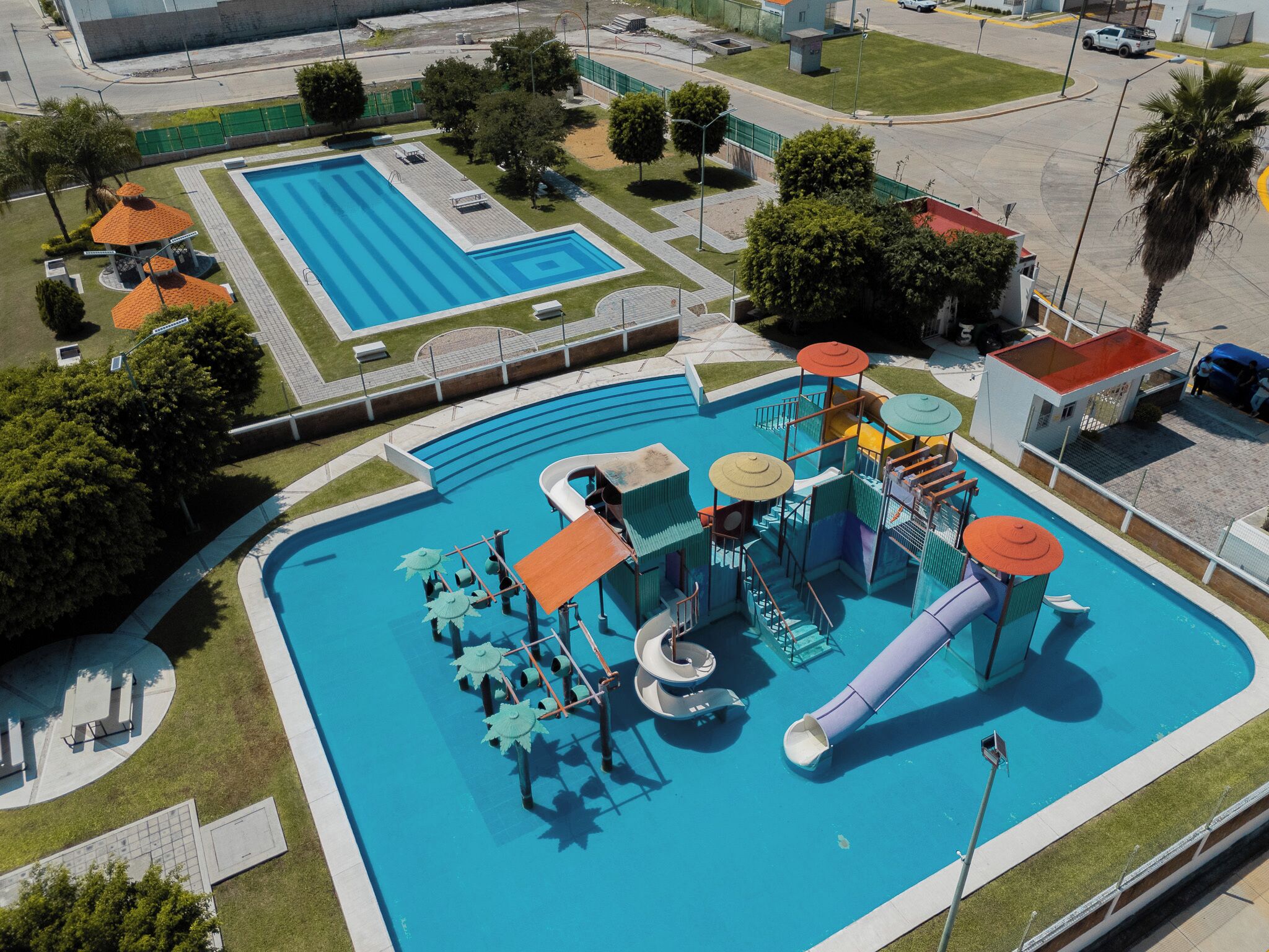 Una grande piscina con uno scivolo acquatico e strutture gioco.
