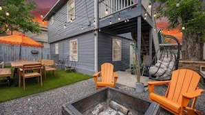 Et toetagers hus med en terrasse, udendørs møbler og et bålsted.