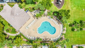 Vista aérea de un resort con piscina, sillas de descanso, palmeras y un área techada.