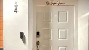 A white door with a keypad lock and a doorbell. The number 34 is visible on the wall to the left.