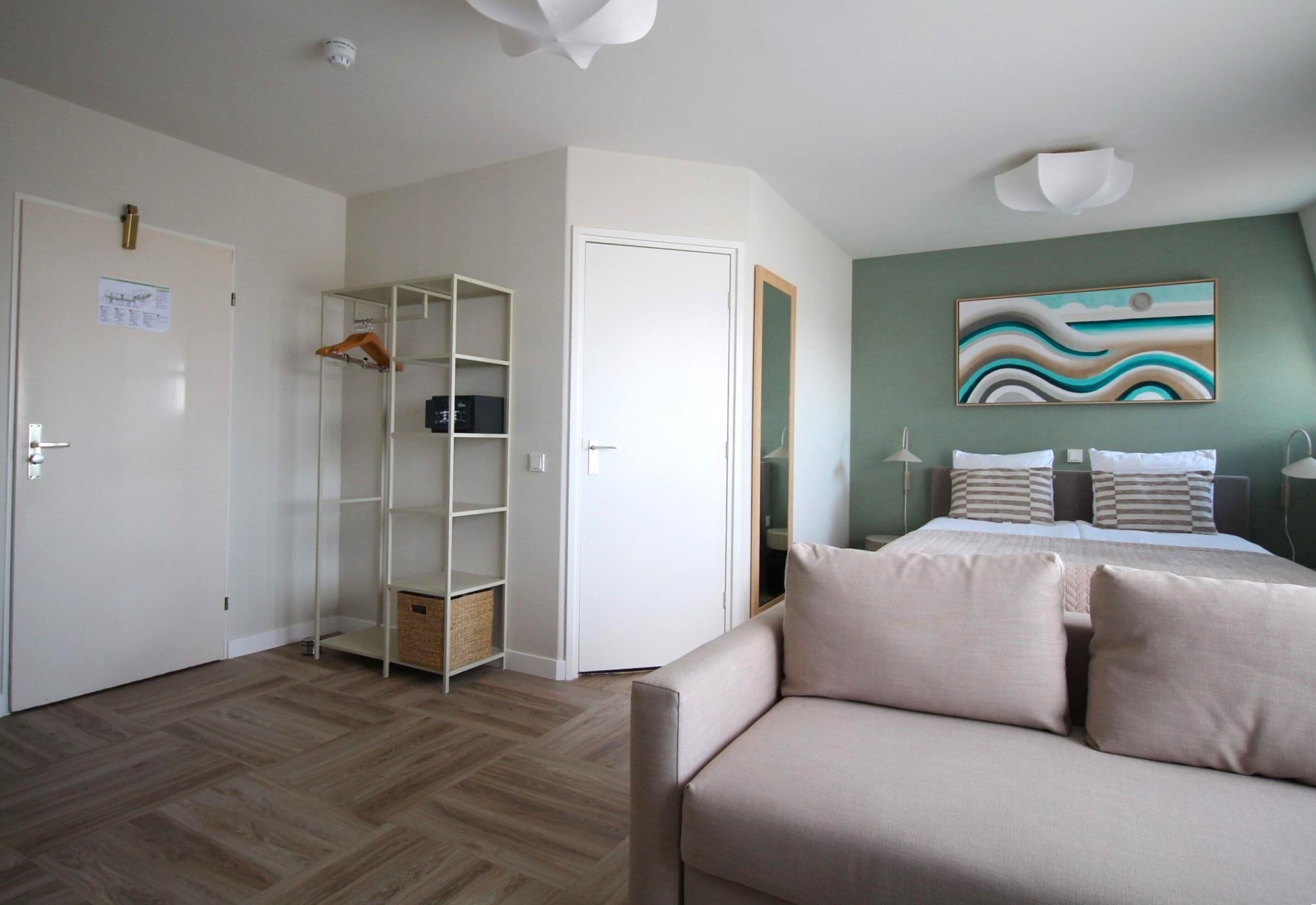 A bedroom with a bed, a sofa, a wardrobe, and a painting on the wall.