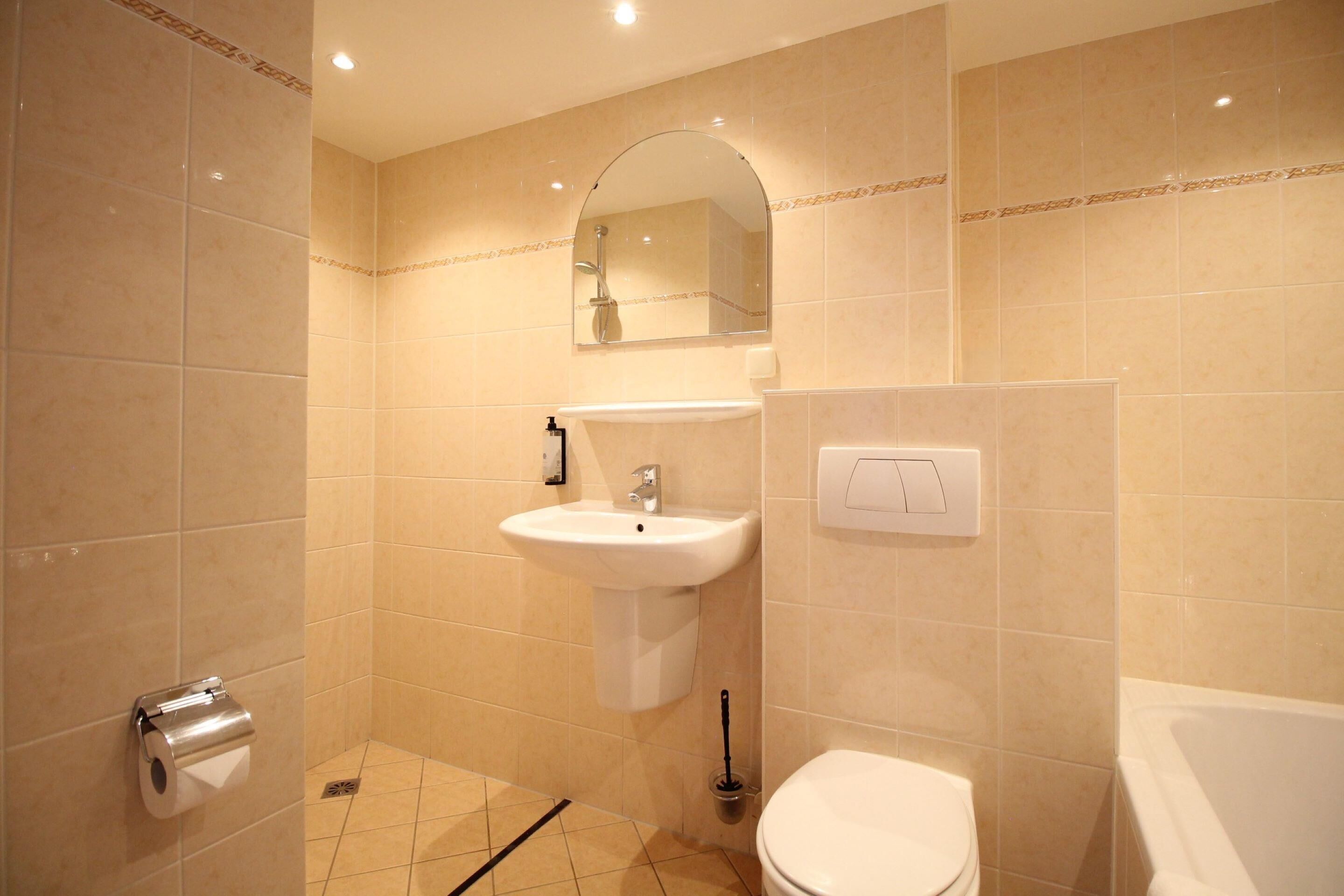 Een badkamer met een wastafel, spiegel, toilet en douche.