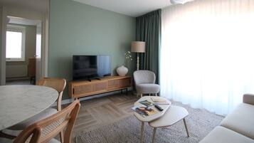 Una sala de estar moderna con televisor, asientos y comedor.