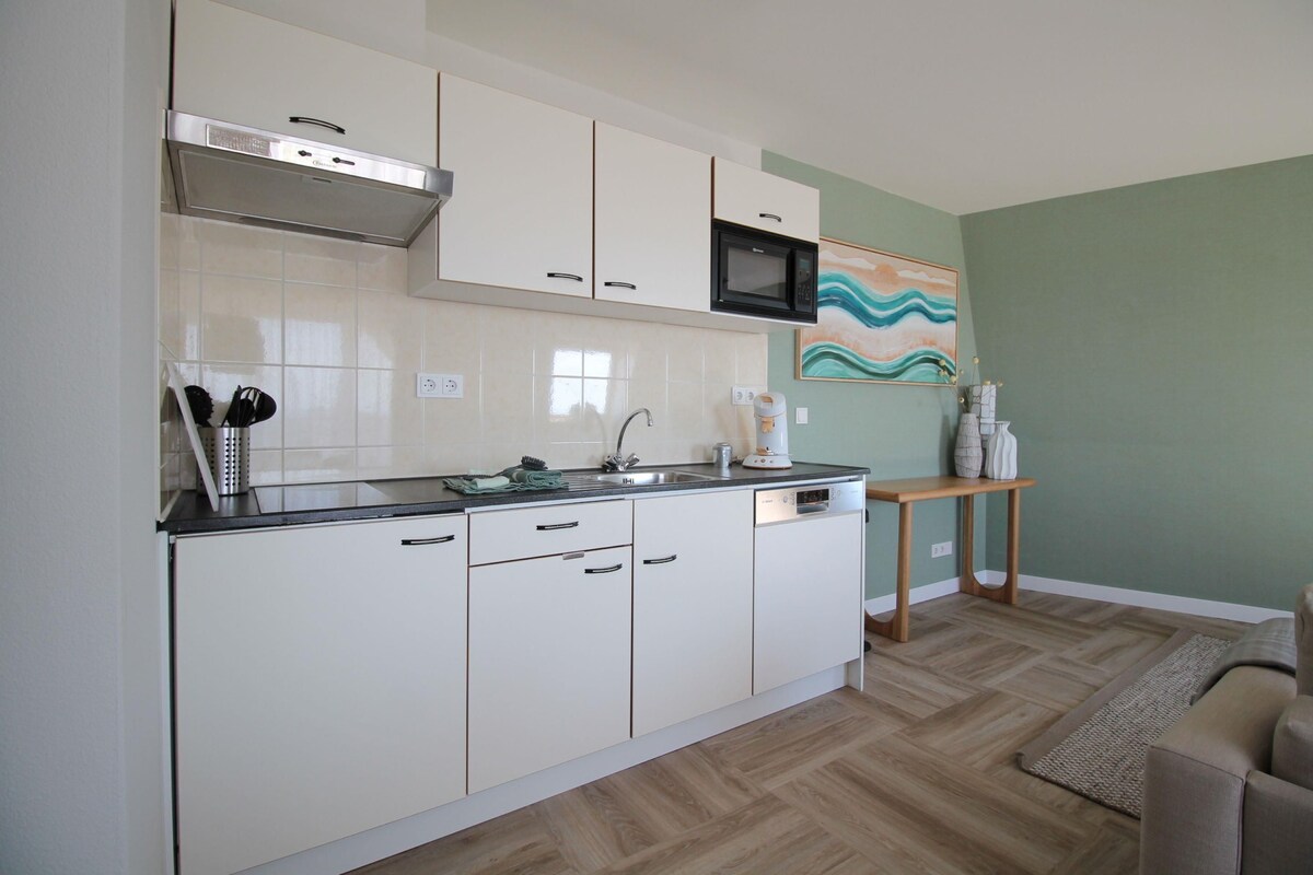 A compact kitchen with white cabinets, a microwave, and a sink.