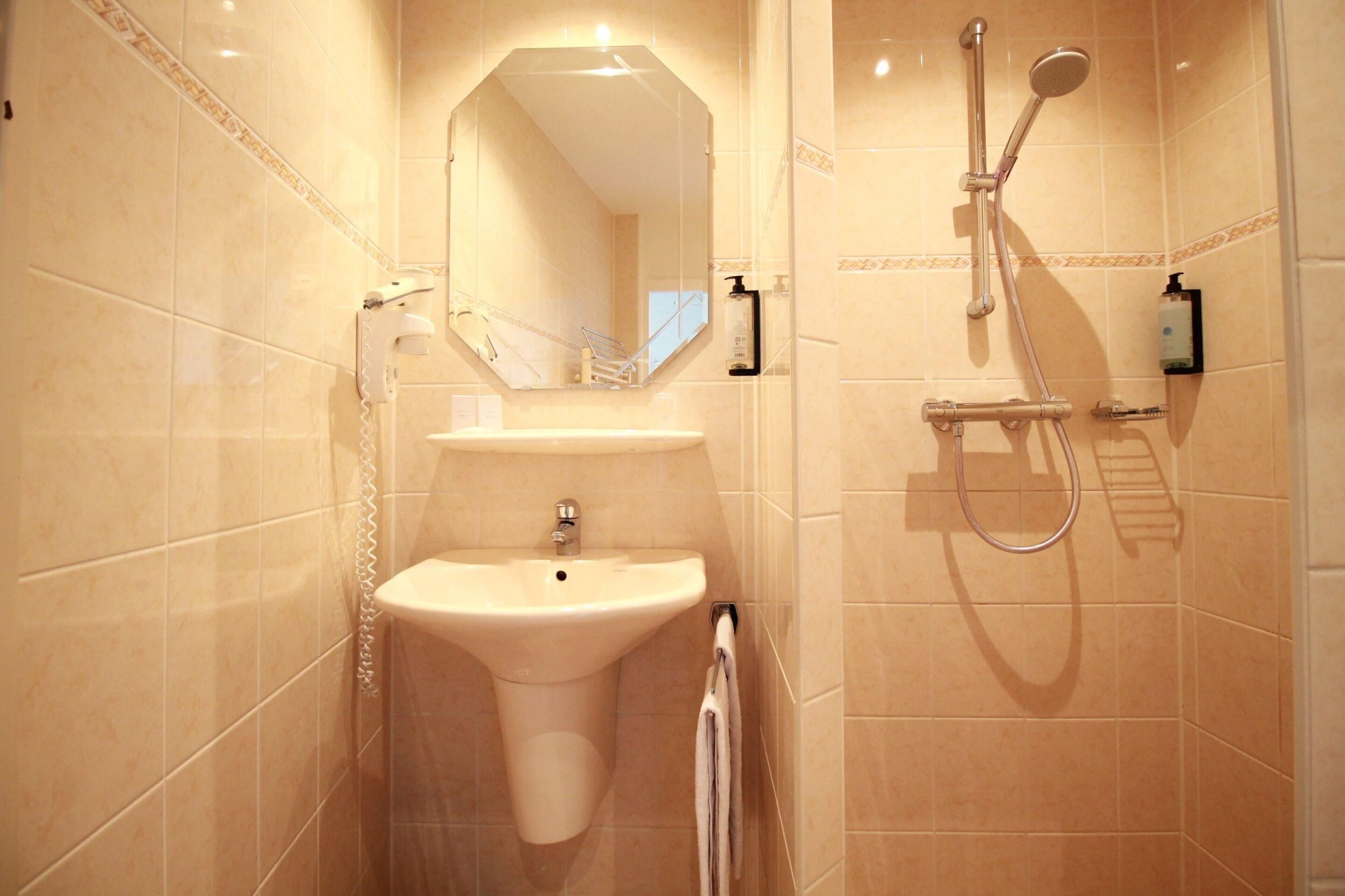 Un baño con lavamanos, espejo y ducha.