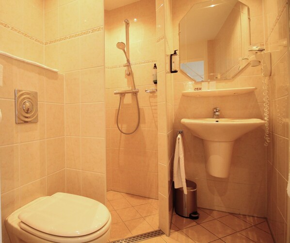 A bathroom with a toilet, a shower, and a sink.