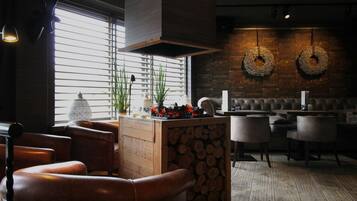 Een gezellig restaurant met houten meubels, een centraal eiland met planten en een met kransen versierde bakstenen muur.