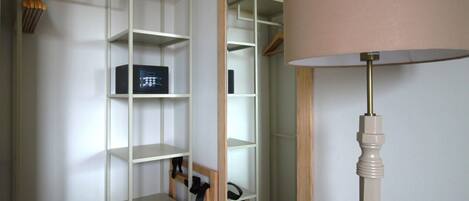 A room with a mirrored wardrobe, a standing lamp, and open shelving.