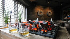 A cozy bar area with a fireplace, wooden counter, and two glasses of whiskey. - Best Western Beach Hotel Bergen Aan Zee (Bergen aan Zee)
