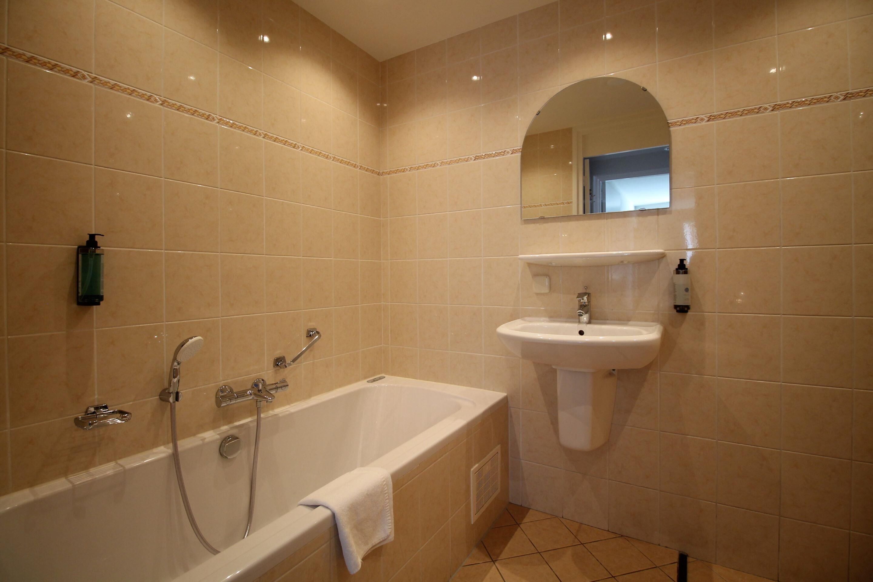 Een badkamer met een bad, een wastafel en een spiegel.