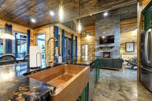 A modern kitchen with a large island, stone accents, and a fireplace.