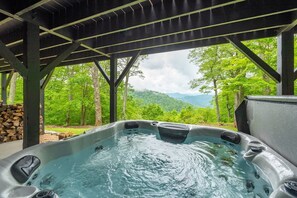 Ein Whirlpool unter einer Pergola mit Blick auf eine bewaldete Bergkette.
