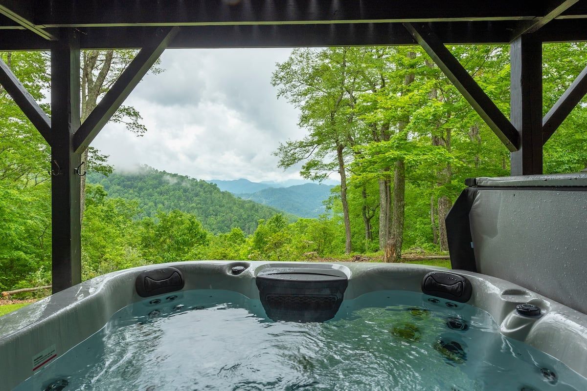 Un jacuzzi con vistas a una cadena montañosa boscosa.