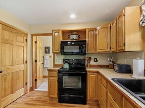 A kitchen with wooden cabinets, a black stove, a microwave, and a toaster.