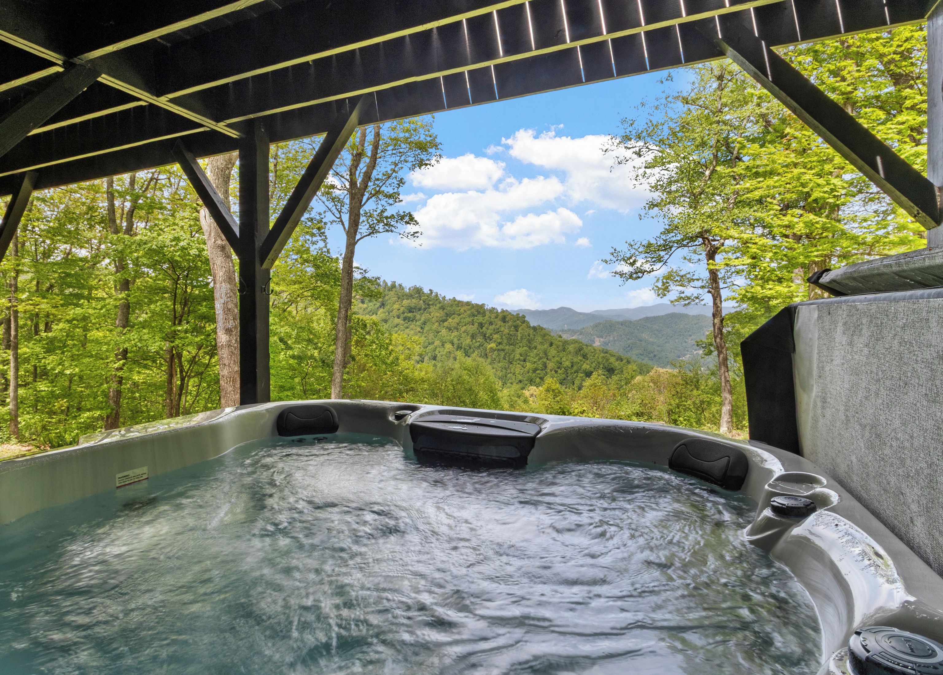 A hot tub with a view of a forested mountain landscape.